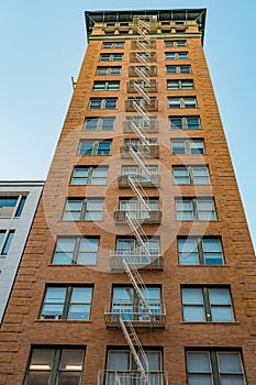 Tall brick building with external fire escape against a clear blue sky