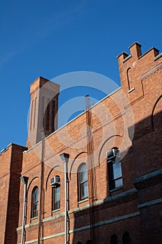 a tall brick building with two clock towers in front of blue sky