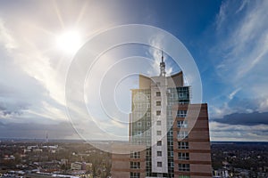 A tall building made of glass. Blue sky and bright sun