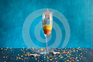Tall champaign glass filled with colorful confetti and wooden heart celebration background