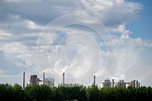 Tall chimneys of a factory with smoke rising up, polluting the atmosphere. Air pollution concept.