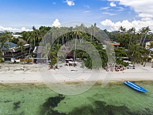 Tall coconut trees, resorts and al fresco restaurants line Alona Beach in Panglao Island, Bohol, Philippines