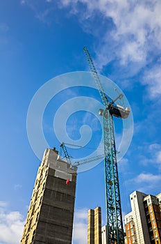 Tall crane operating on a construction site of high-rise apartments in England, UK