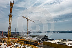 Tall cranes and Seattle waterfont with ferris wheel surround construction