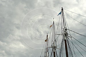 Tall elegant lines of ship masts against grey stormy skyline outside