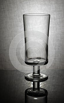 empty beer glass with reflection on textured gray background