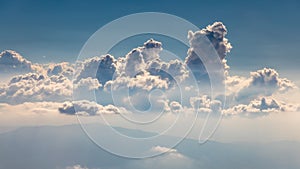 Tall fluffy clouds at eye level and the hint of mountain range below