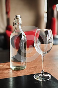 Tall glass bottle of water and an empty glass on a wooden table