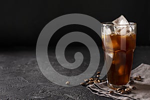 tall glass cold brew coffee with ice on black