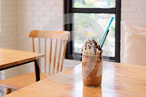 Tall glass of delicious cold iced coffee float or milkshake topped with ice cream or cream on a rustic wooden counter for