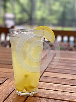 Tall glass of lemonade on teak patio table.