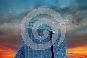 A tall glass modern office building with a blue sky and powerful red clouds at sunset in downtown Atlanta