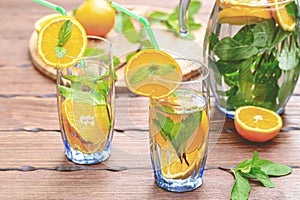 Tall glasses of iced tea with a few slices of oranges scattered on a wooden surface