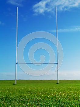 Tall goal post for Irish National sport rugby, hurling, gaelic football and camogie on a green training pitch, blue cloudy sky