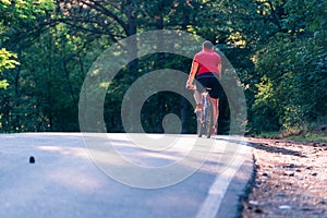 Tall handsome biker rides his bicycle on sunset in a lovely magical forest