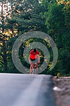 Tall handsome biker rides his bicycle on sunset in a lovely magical forest