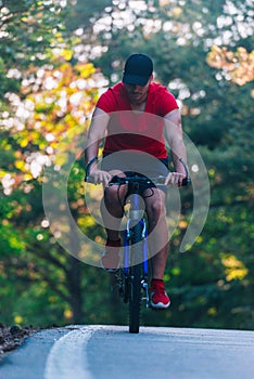 Tall handsome biker rides his bicycle on sunset in a lovely magical forest