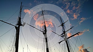 A tall, handsome dark masts of an old ship on the background of purple colored sunset sky. Romantic journey