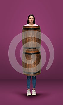 Tall high woman and long barrel isolated on purple studio background. Unusual delighted and long