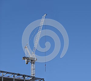 Tall hoisting tower crane on the top of being constructed of modern high skyscraper building photo