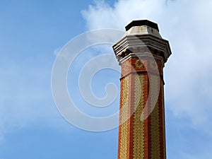 Tall industrial chimney stack of yellow and red brick of octagonal base