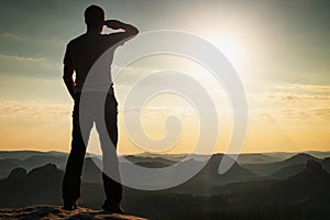 Tall man with raised arm for shadowing eyes photo