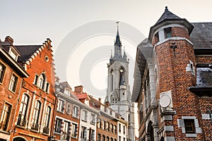 Tall medieval bell tower rising over the street with old european houses, Tournai, Walloon municipality, Belgium