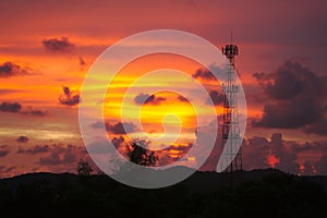 Tall mobile cell phone tower on the high hill sending signal to connect people around the world in the evening when sunset