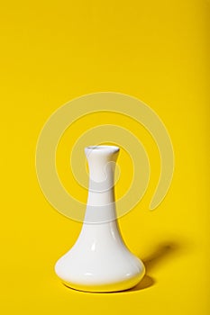 Tall narrow white vase on a yellow background