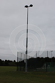 Tall outdoor stadium lights used to light up a pitch, taken on a cloudy day