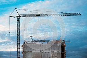 Tall prefabricated residential building construction site with old crane