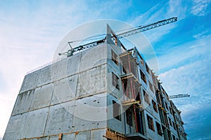 Tall prefabricated residential building construction site with old crane