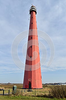 A tall red lighthouse beside the beach at Atlantikwall, Netherlands