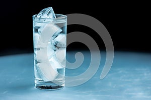 Tall, refreshing glass full of water and ice cubes above a planet