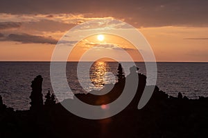 Tall rock formations with sunset over the Pacific ocean in the background