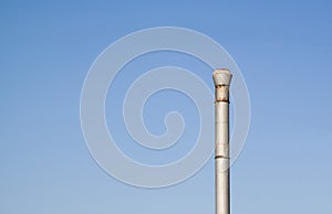 Tall rusty silver pole on a clear blue sky background