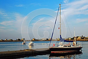 A tall sailboat is tied at a calm harbor