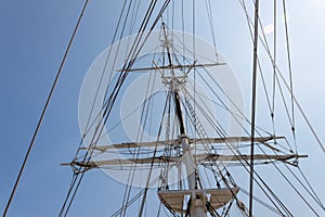 Tall ship mast and rigging in morning sun against a blue sky