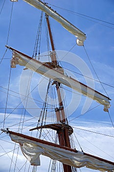 Tall ship mast with rolled sails, sky in background