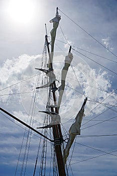 Tall ship mast with rolled sails, sky in background