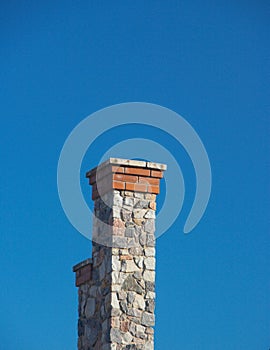 Tall stone chimney against clear deep blue sky 2