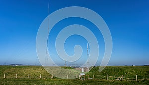 Tall telecommunications mast secured by support wires on the top of White Sheet Hill in Wiltshire, UK