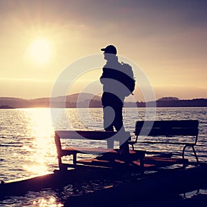 Tall tourist with backpack walk on beach at pedal boat in the sunset. Autumn at sea