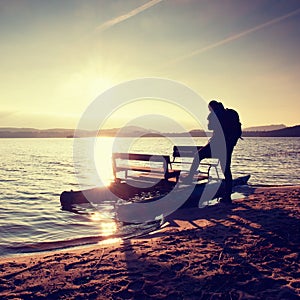 Tall tourist with backpack walk on beach at pedal boat in the sunset. Autumn at sea