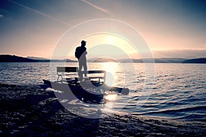 Tall tourist with backpack walk on beach at pedal boat in the sunset. Autumn at sea