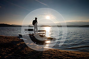 Tall tourist with backpack walk on beach at pedal boat in the sunset. Autumn at sea