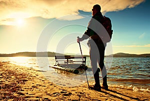 Tall tourist walk on beach at paddle boat in the sunset