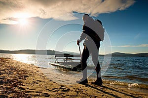 Tall tourist walk on beach at paddle boat in the sunset