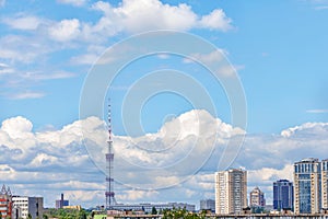 A tall TV tower against a blue sky in an urban summer landscape