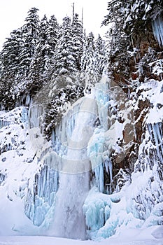 Tall Waterfall in Snow Covered Winter Landscape